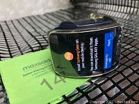 Samsung Gear smartwatch on with installation prompt visible on the screen, showing the device in powered on state and a black silicone strap.