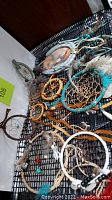 Overview of multiple vintage dreamcatchers laid on a black mesh surface showing various sizes, colors, and decorative elements including feathers and turquoise stones.
