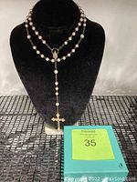 Full view of the rosary necklace displayed on a black velvet bust alongside the green gift box containing the rosary.