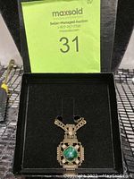Full view of necklace inside black gift box with auction label