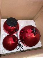 Three red spherical Christmas ornaments inside a box with styrofoam packaging.