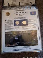 Informational page about Delaware state quarter showing the coin from Philadelphia and Denver mints along with state seal, flag, historical context and image of a landmark.
