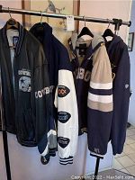 Four outerwear pieces on rack: leather jacket, varsity jacket, hooded fleece, hooded sweatshirt