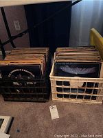 View of two plastic crates filled with assorted vinyl records showing visible labels and album artwork.