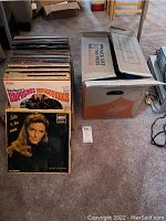 Box of vintage vinyl records including The Supremes Reflections album visible on top and several other LPs and 45s behind.