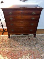 Full-frontal view of mahogany bureau on a patterned rug