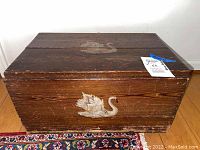 Front view of the antique wooden chest showing the hand-painted white swan on the darker wood surface.