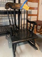 Black wooden rocking chair with painted floral detail on backrest, seat, and rockers