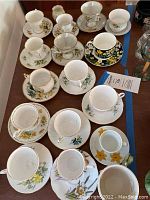 Overall view of eleven teacup and saucer sets arranged on table