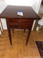 Front angled view of antique mahogany side table showing two drawers and original knob hardware.