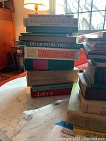 Stack of gardening books including Dictionary of Plant Names, Philadelphia Gardener Book, Weeds of the Northeastern Region, Bulb Forcing, Dictionary of Horticulture, The Wise Gardener's [title partially obscured]