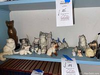 Shelves with assorted ceramic and porcelain cat figurines in various poses and colors.