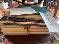 Stack of assorted flower arranging books showing titles and covers on a table.