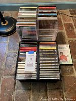 Stack of music CDs in jewel cases, some in clear plastic holders. Visible titles include Garth Brooks and assorted compilation albums.
