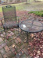Patio chair and round table set outdoors on brick patio, showing overall set and path surrounding it.