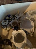 Ceramic sugar and creamer sets with floral and colorful designs, some with lids, shown together in a corner.