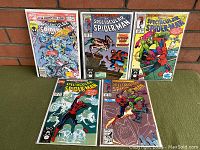 Full view of all 5 comic books showing front covers and arrangement on green carpet in front of brick wall.
