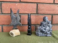 Photo showing all three sculpture carvings together (bird on antler base, black totem figure, seated figure with animal).