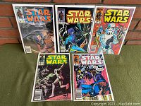 Five Marvel Comics Star Wars issues 95-99, all in protective bags, arranged on a green surface against a brick wall.