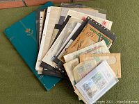 Green three-ring stamp album binder with assorted loose pages, envelopes, and stamp sheets