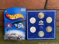 Front view of sealed Hot Wheels Blue Jays 25th season promotional car and coin display board with six commemorative coins.