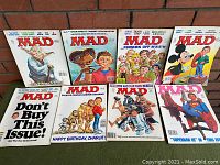 Photo shows all 8 vintage Mad Magazines laid out, featuring a variety of pop culture themed illustrated covers including Star Wars, E.T., MASH, Superman, and Mickey Mouse.