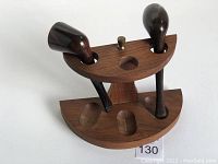 Two smoking pipes inserted in half-moon shaped wooden pipe rest rack with mechanical brass pivot, slots for three pipes, dark wood finish.