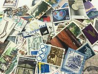 Close-up photo of assorted used worldwide postage stamps depicting various themes, countries, and colors