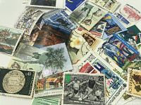 Close-up of a variety of postage stamps with different designs and cancellation marks, showing flowers, architecture, and colorful artwork.