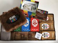 Photo showing fuzzy brown plush pouch with Bears vs Babies logo, partially open game box with stacked cards, instruction cards, and various colorful monster and baby cards.
