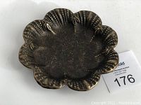 Top view of the flower-shaped brass plate showing petal and textured details.