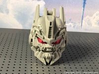 Close-up image of the gray Transformer head figurine showing detailed mechanical design and red eyes