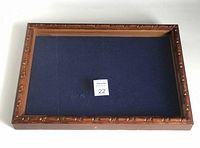 Top down view showing the full rectangular display box with carved wooden frame and blue fabric interior.