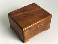 Closed view of a square wooden box with a smooth medium brown finish and dovetail corners.