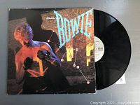 Photo of vinyl record partially pulled out of album cover showing David Bowie image and album title