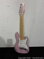 Full view of pink Stage One SEG-138 mini electric guitar showing body, neck, and headstock.
