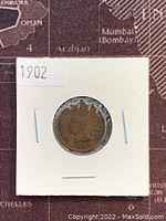 Obverse view of 1902 US Indian Head penny, showing Lady Liberty with Indian feather headdress dated 1902 in a white cardboard holder.