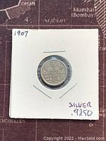 Front side of the coin showing denomination 5 cents, year 1907, and silver purity 92.5% marked on holder.