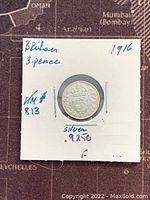 Obverse of 1916 British 3 Pence silver coin showing King George V profile inside white holder with inscriptions.