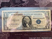 Front side of a 1935F US one dollar banknote showing George Washington portrait, serial number, blue seal, and signatures.