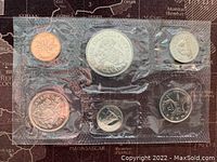 Front side of 1971 Canadian proof-like coin set showing detailed designs on 1 cent, 5 cent, 10 cent, 25 cent, 50 cent, and larger commemorative coins in sealed plastic.