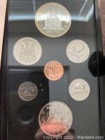 Front view of 1976 Canadian Silver Specimen Double Dollar Set coins in black protective case, showing main silver dollar and other coins arranged around it.