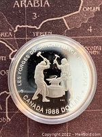 Front side of the 1988 Canadian silver proof dollar coin showing two blacksmith figures at an anvil commemorating Saint-Maurice Ironworks.