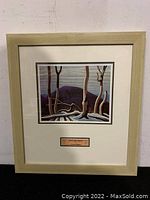 Full view of the framed print showing the artwork, light wood frame, cream mat, and plaque with title and artist's name.