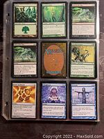 Close up photo showing nine Magic: The Gathering cards in a plastic collector sheet including Forest, Verdant Justice, Call of the Herd, Phyrexian Spree, Thoughtcast, and Ornithopter cards.
