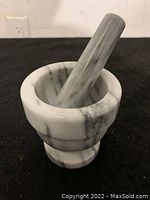 Marble stone mortar with pestle placed inside, showing size and shape