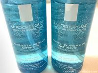 Close-up of two bottles showing the product label and liquid inside the translucent blue bottle with white pump caps.