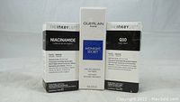 Three boxed skincare serums in original packaging: The Ink Key List Niacinamide, Guerlain Paris Midnight Secret, and The Ink Key List Q10