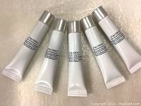 Five white squeeze tubes with silver caps showing Shiseido branding and product details, arranged in a row on a textured surface.
