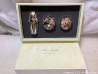 Opened box showing three skincare products arranged in foam cutouts inside elegant branded outer box.